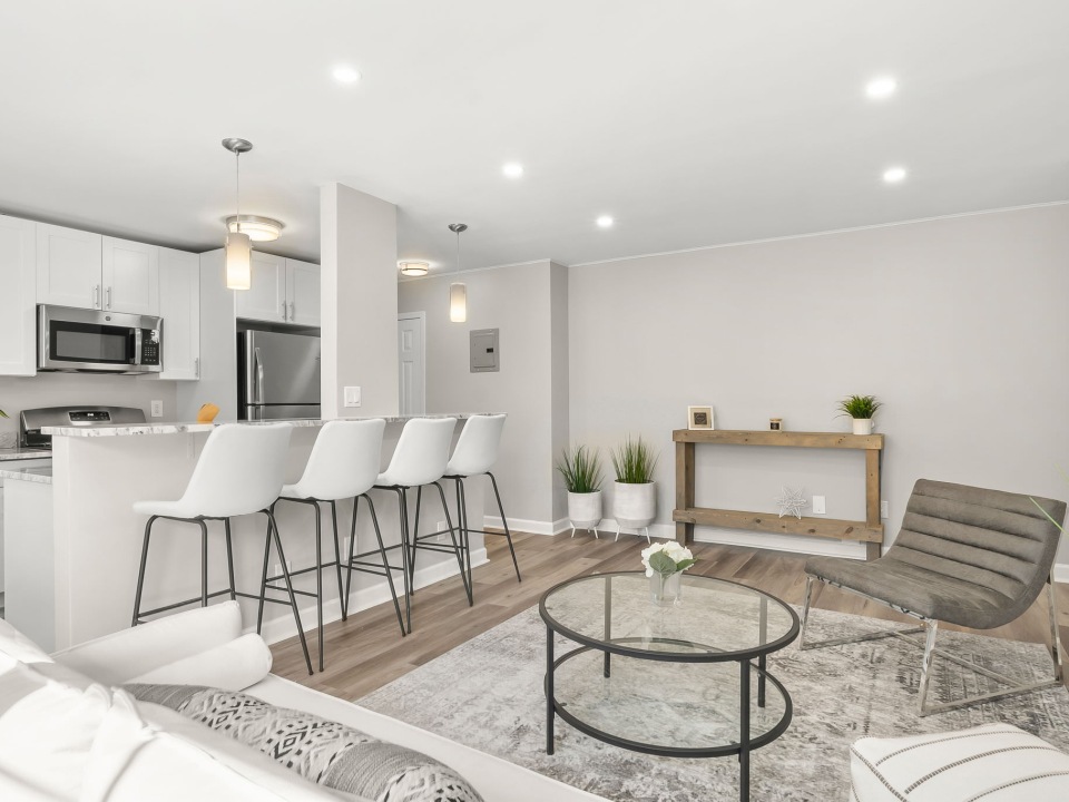a living room and kitchen with barstools